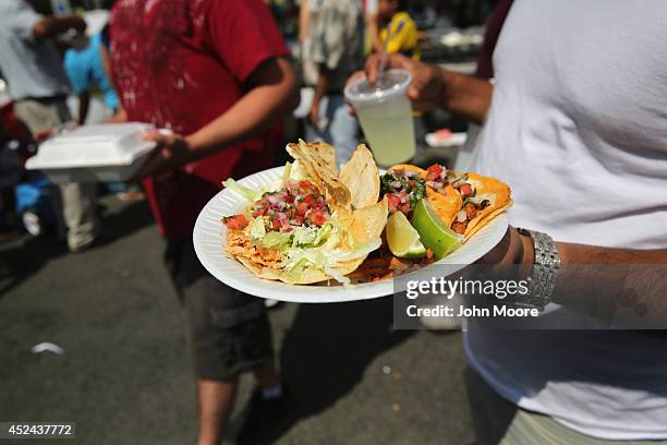 Man carries a plate of tacos at the Hispanic Heritage Festival on July 20, 2014 in Valhalla, New York. Thousands of people gathered for the event to...