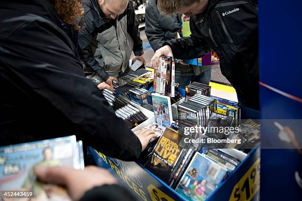 Shoppers look through a bin of DVD movies at a Best Buy Co. Store ahead of Black Friday in Peoria, Illinois, U.S., on Thursday, Nov. 28, 2013. U.S....