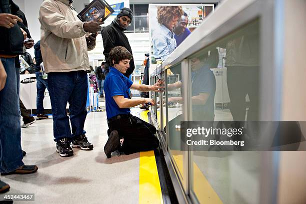 Sales associate locks a cabinet containing tablet devices as customers look on at a Best Buy Co. Store ahead of Black Friday in Peoria, Illinois,...