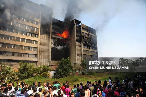 Bangladeshi bystanders watch as smoke and flames billow from a burning garment factory in the key garment manufacturing hub of Gazipur on the...