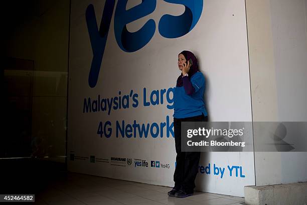 An woman talks on a mobile phone while standing in front of an advertisement for YTL Communications Sdn. Bhd. In Kuala Lumpur, Malaysia, on Sunday,...