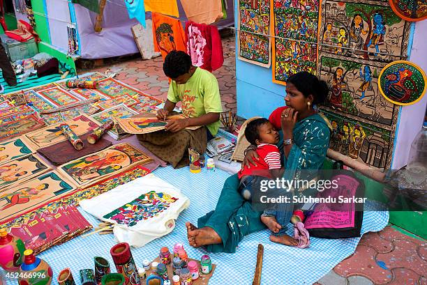 Man engaged in making handicraft products while his wife takes care of their sleeping child. Handicraft products of West Bengal are world famous....