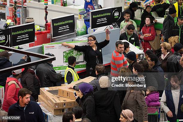 An employee shouts to colleagues as customers gather around a near-empty display of televisions during a Black Friday discount sale inside an Asda...