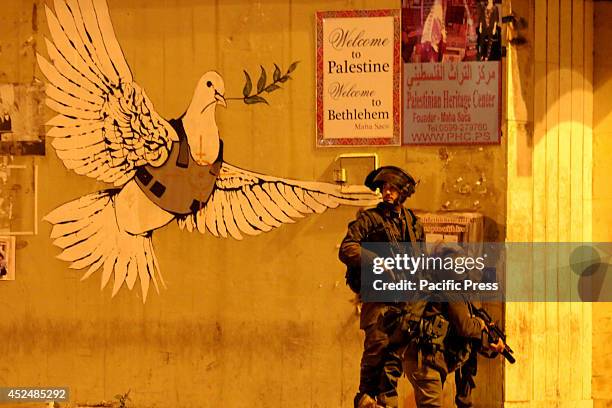 Two Israeli soldiers take cover behind a wall with the famous dove of peace by Banksy in the Bethlehem streets. After several days of calmness in the...