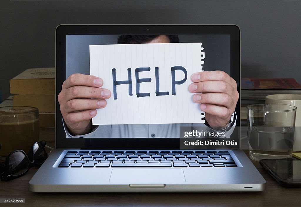 Hands holding help sign out of laptop screen
