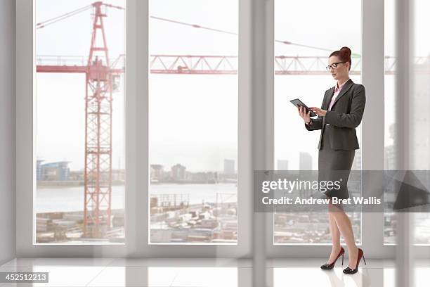 woman uses computer tablet from city apartment - person in suit construction stock-fotos und bilder