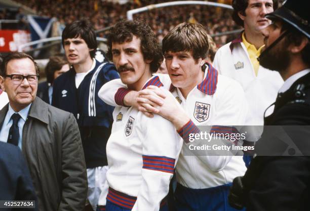 England players Terry McDermott and Emlyn Hughes share a hug as Alan Hansen of Scotland looks on before a Home International match between England...