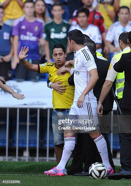 Real Madrid's new signing James Rodriguez of Colombia tries to prevent security from manhandling a young Colombian fan during his unveiling as a new...