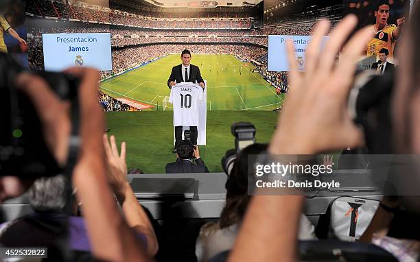 James Rodriguez holds his new Real shirt during his unveiling as a new Real Madrid player at the Santaigo Bernabeu stadium on July 22, 2014 in...