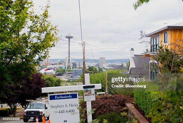 The Space Needle stands past a "For Sale" sign displayed in front of a house in Seattle, Washington, U.S., on Sunday, July 20, 2014. Sales of...