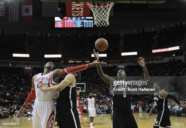 Dwight Howard of the Houston Rockets fights for a rebound with Brook Lopez and Andray Blatche of the Brooklyn Nets during the game at Toyota Center...