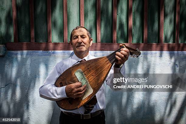 Vasile Nica plays a cobza at his place in Barboi village, 260 kilometers west from Bucharest, on June 27, 2014. AFP PHOTO / ANDREI PUNGOVSCHI