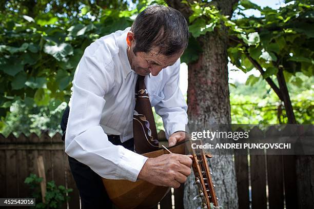 Vasile Nica tunes a cobza at his place in Barboi village, 260 kilometers west from Bucharest, on June 27, 2014. AFP PHOTO / ANDREI PUNGOVSCHI