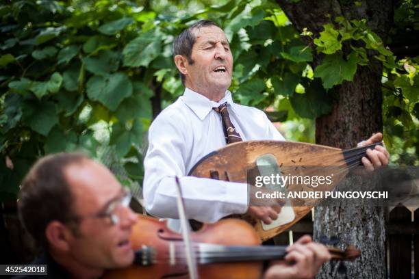 Vasile Nica sings and plays a cobza at his place in Barboi village, 260 kilometers west from Bucharest, on June 27, 2014. AFP PHOTO / ANDREI...