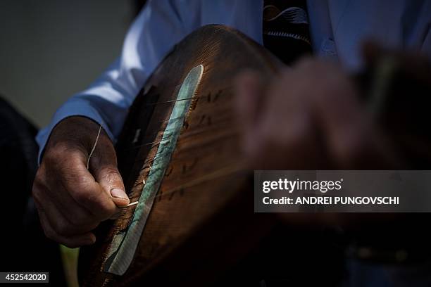 Vasile Nica plays a cobza at his place in Barboi village, 260 kilometers west from Bucharest, on June 27, 2014. AFP PHOTO / ANDREI PUNGOVSCHI