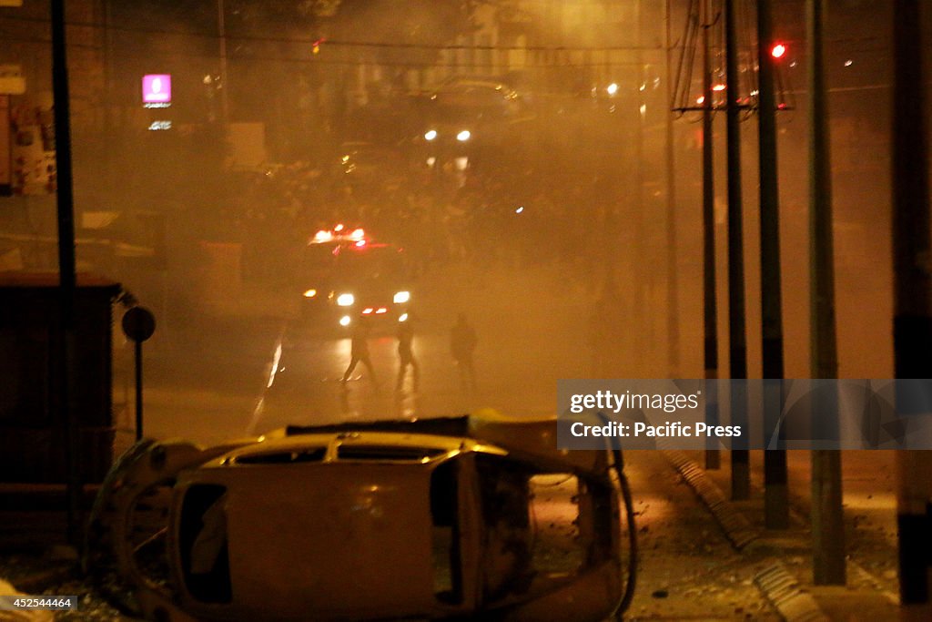 Behind plumes of tear gas smoke, a few masked Palestinian...