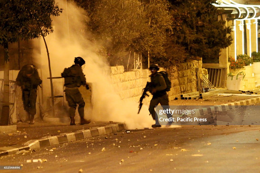 Israeli soldiers run as a tear gas canister lands near them...