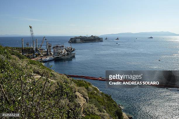 The wreck of the Costa Concordia cruise ship is towed away in front of the harbour of Isola del Giglio, after it was refloated using air tanks...