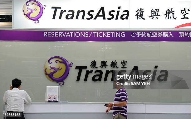 Local journalists wait in front of a TransAsia reservations desk at the Sungshan airport in Taipei on July 23, 2014. More than 40 people were killed...