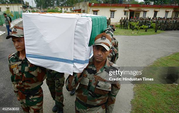 Indian army soldiers carry a flag-draped coffin containing the body of martyr NK Mong Chon P during a wreath-laying ceremony on July 23, 2014 in...