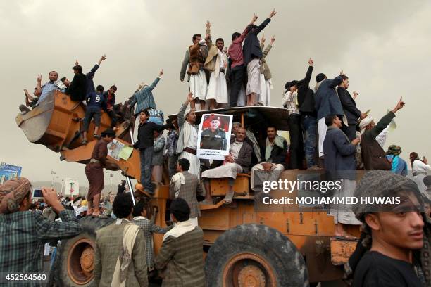 Yemeni mourners standing on a bulldozer hold portraits of armoured brigade's commander, General Hamid al-Qushaibi who was killed by Shiite rebels who...