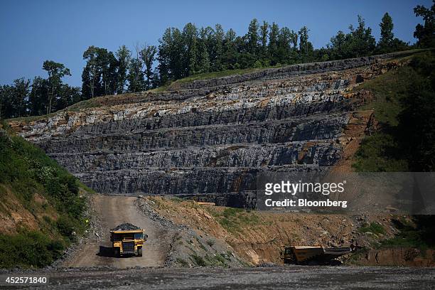 Dump trucks move loads of rock blasted out from a new segment of U.S. Highway 460, part of the Appalachian Development Highway System, under...