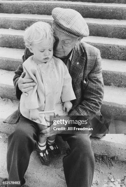 Young girl sits on the knee of an elderly man in Llandudno, Wales, 1974.