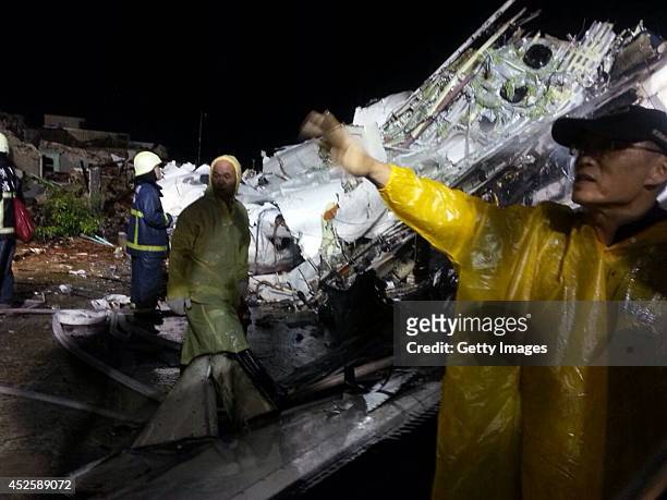 Rescuers check the wreckage of a TransAsia Airways twin turboprop plane that crashed July 23, 2014 in a village near Magong, Taiwan of China. The...