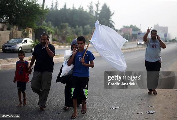 Palestinians fleeing Khan Yunis to safe areas hold white flags to show that they are not dangerous on July 24 as the Israeli shelling on Gaza within...