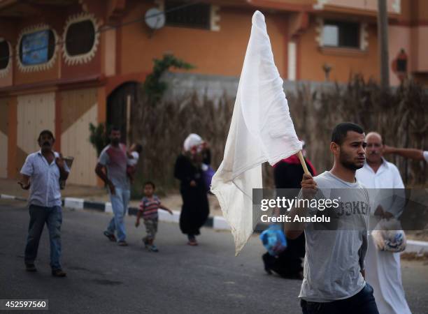 Palestinians fleeing Khan Yunis to safe areas hold white flags to show that they are not dangerous on July 24 as the Israeli shelling on Gaza within...