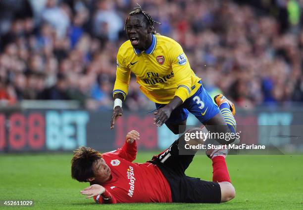 Bacary Sagna of Arsenal is fouled by Bo-Kyung Kim of Cardiff at Cardiff City Stadium on November 30, 2013 in Cardiff, Wales.