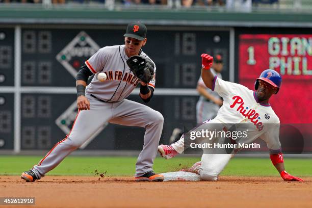 Jimmy Rollins of the Philadelphia Phillies slides into second base with a double in the first inning as Ehire Adrianza of the San Francisco Giants...