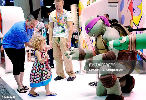 Two year old Ellie Campbell, along with her aunt Jen Pike of Austin, Texas, gets a high-five from the Teenage Mutant Ninja Turtle character Donatello...