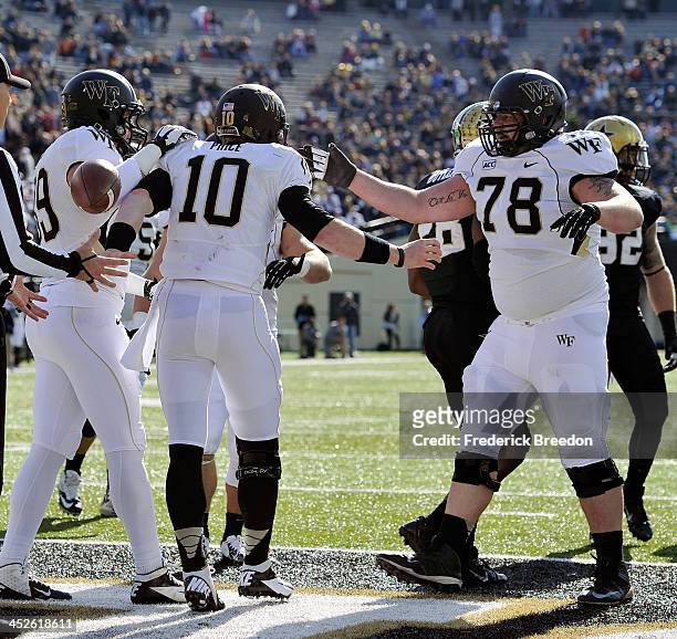 Quarterback Tanner Price of the Wake Forest Demon Deacons is congratulated by teammate Tyler Hayworth after scoring a touchdown against the...