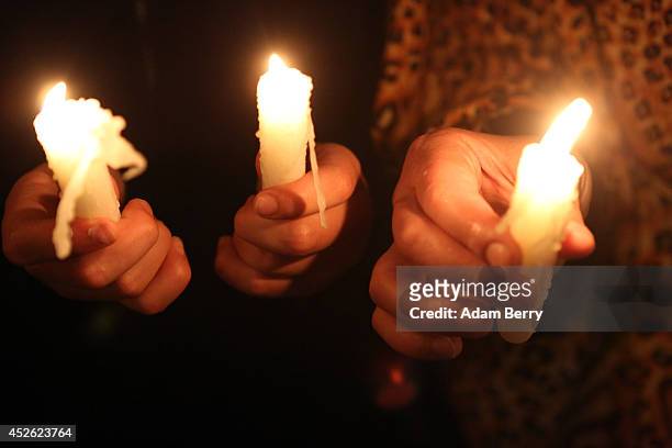 Demonstrators hold candles in the rain during a memorial vigil of those killed during the continued violence in Gaza, on July 24, 2014 in Berlin,...