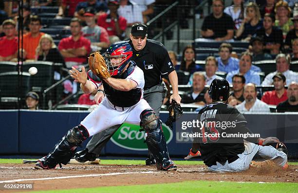 Marcell Ozuna of the Miami Marlins scores the go-ahead run in the ninth inning against Evan Gattis of the Atlanta Braves at Turner Field on July 24,...