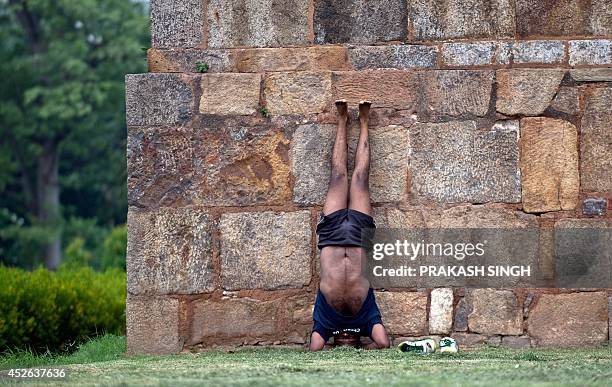 An Indian man executes a headstand or shirshasana yoga in Lodhi Gardens in New Delhi on July 25, 2104. The gardens which form a park in the southern...