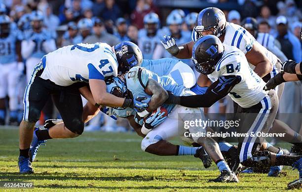 Duke Blue Devils linebacker David Helton and defensive end Kenny Anunike stop North Carolina Tar Heels running back T.J. Logan at the line of...