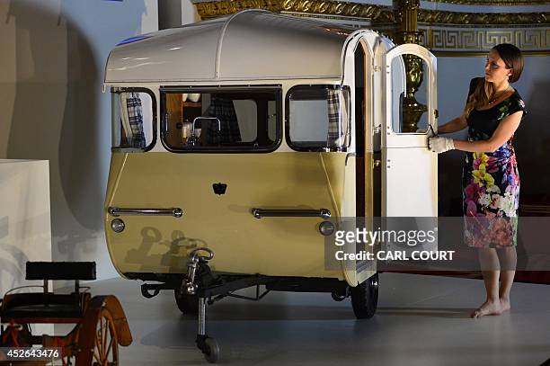 Member of staff poses for photographers with a miniature caravan presented to Britain's Prince Charles and his sister Princess Anne by the Caravan...