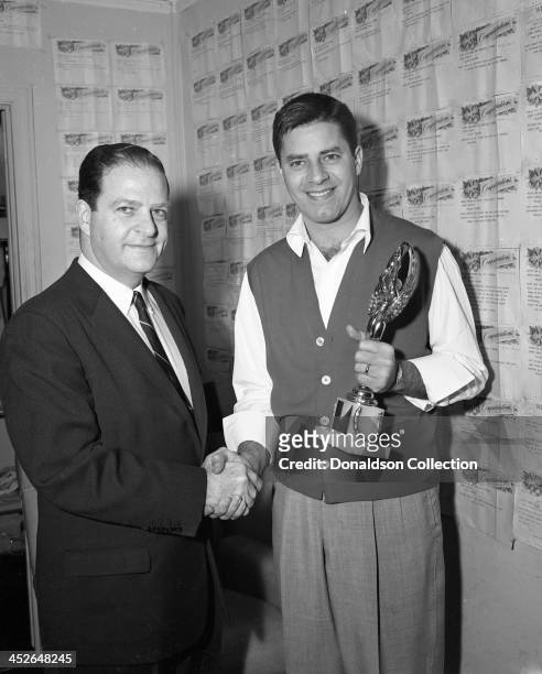 Comedian Jerry Lewis receives an award from a man backstage at a Jerry Lewis show at the RKO Palace Theater on Broadway on February 7, 1957 in New...