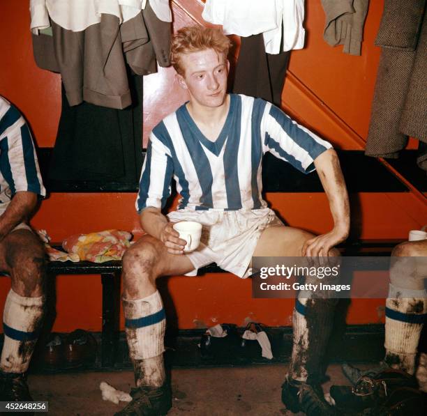 Huddersfield Town player Denis Law enjoys a cup of tea in the dressing room after a game in 1957 in England.