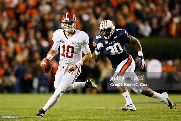 McCarron of the Alabama Crimson Tide runs the ball against the defense of Dee Ford of the Auburn Tigers in the third quarter at Jordan-Hare Stadium...