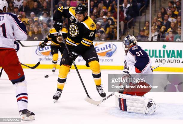 Milan Lucic of the Boston Bruins tips the puck in front of Curtis McElhinney of the Columbus Blue Jackets for a goal in the first period during the...