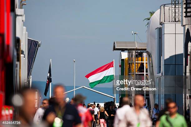 Hungarian national flag flaps in the wind as people walk through the paddock during practice ahead of the Hungarian Formula One Grand Prix at...