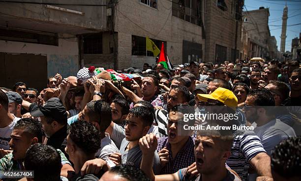 The body of Mohammed al-Araj is carried through the streets to the cemetary during his funeral on July 25, 2014 near Ramallah, West Bank. Al-Araj was...