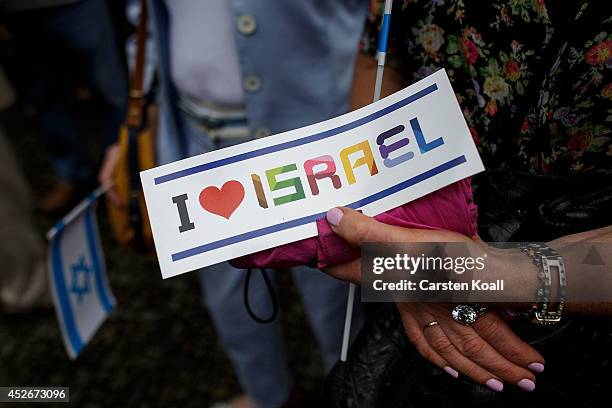 Demonstrator holds a card reading 'I love Israel' and another holds an Israeli flag during a counter demonstration against Al-Quds Day, an event...