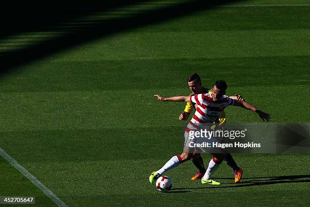 Mark Bridge of the Wanderers holds off the defence of Louis Fenton of the Phoenix during the round eight A-League match between the Wellington...