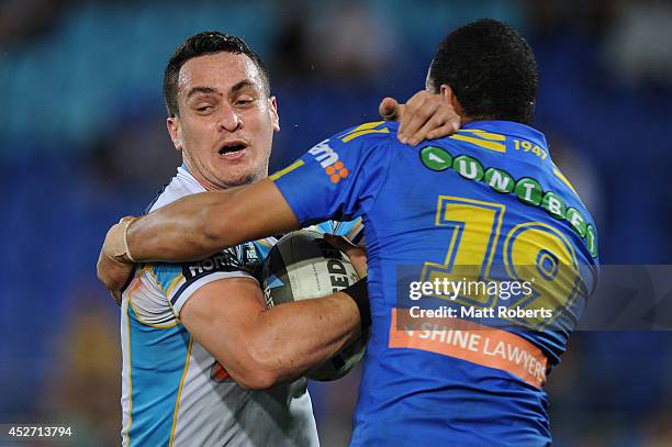 Brad Takairangi of the Titans is tackled by Will Hopoate of the Eels during the round 20 NRL match between the Gold Coast Titans and the Parramatta...