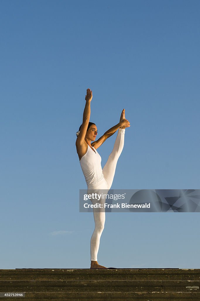 Young woman, wearing a white body suit, is practising Hatha-...