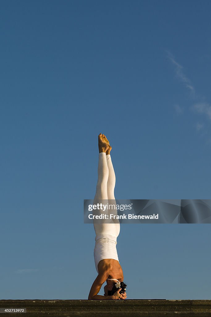 Young woman, wearing a white body suit, is practising Hatha-...